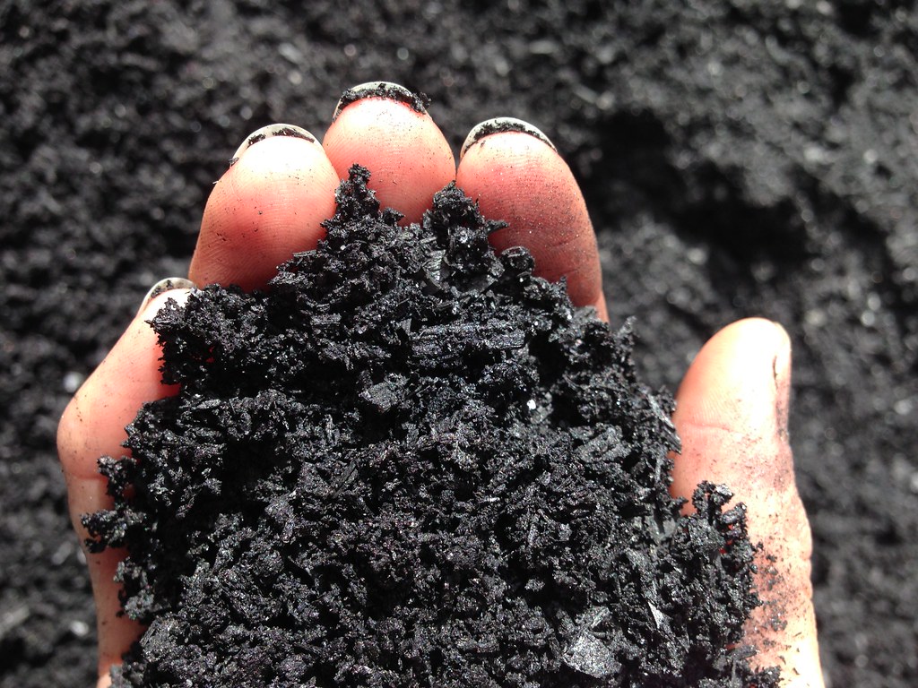 Hand holding soil, only finger tips are seen around the brown soil