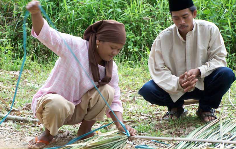 Photo: A woman in Jambi, Sumatra, showing a man how she prepares forest fibers for weaving. Carol Colfer/CIFOR