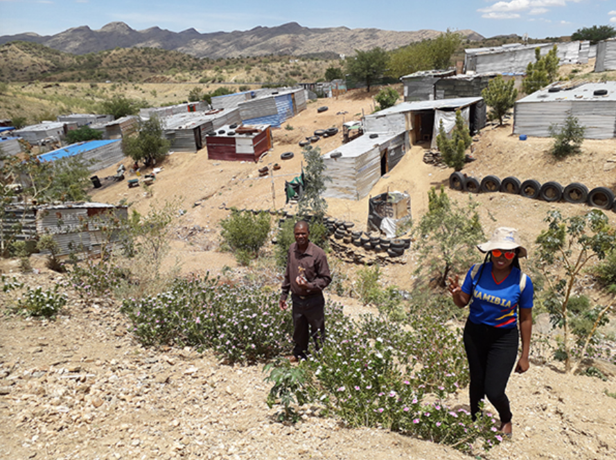 Informal settlement in the drylands of Windhoek, Namibia, with two people in the foreground looking at the camera