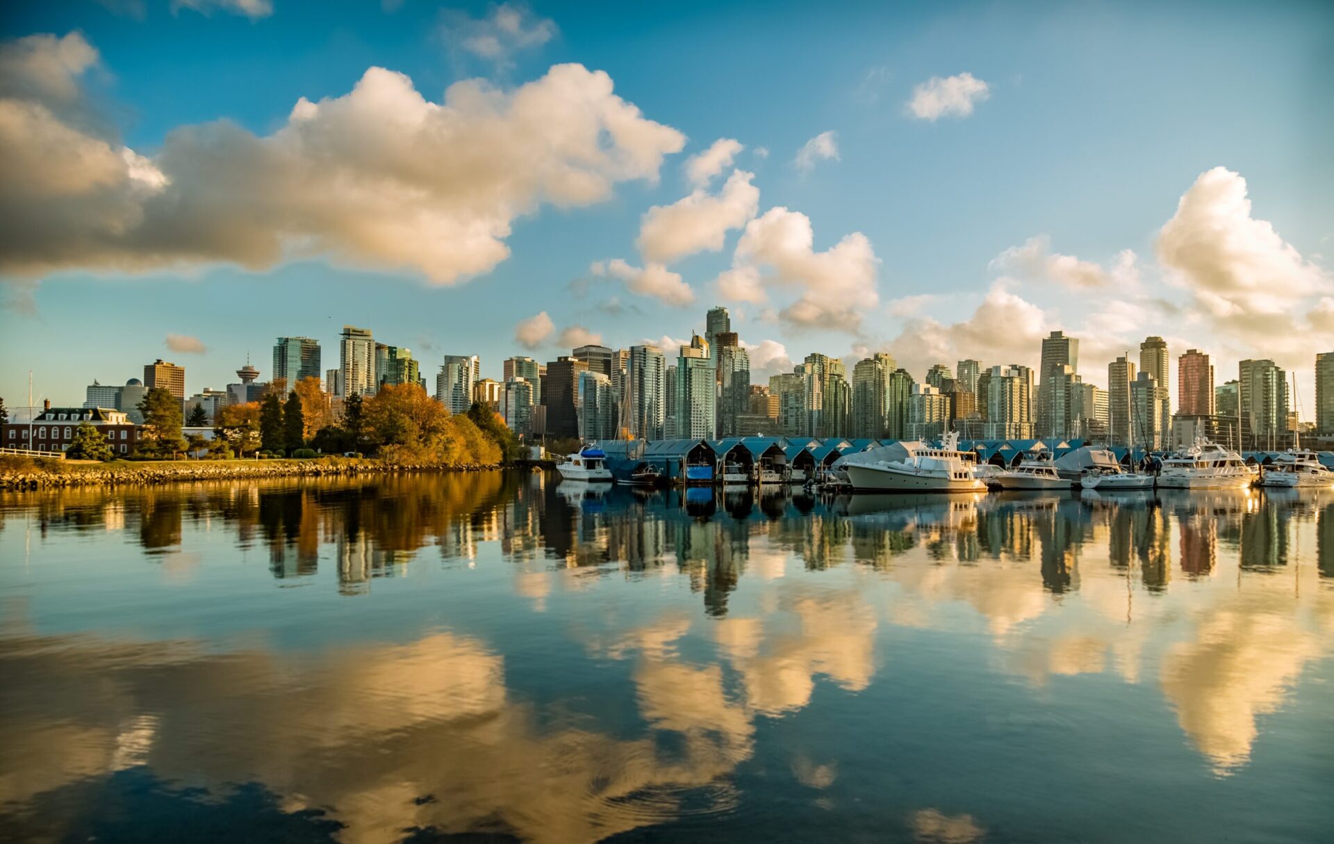 Skyscrapers from the city of Vancouver in front of a blue sky with clouds reflected in the water