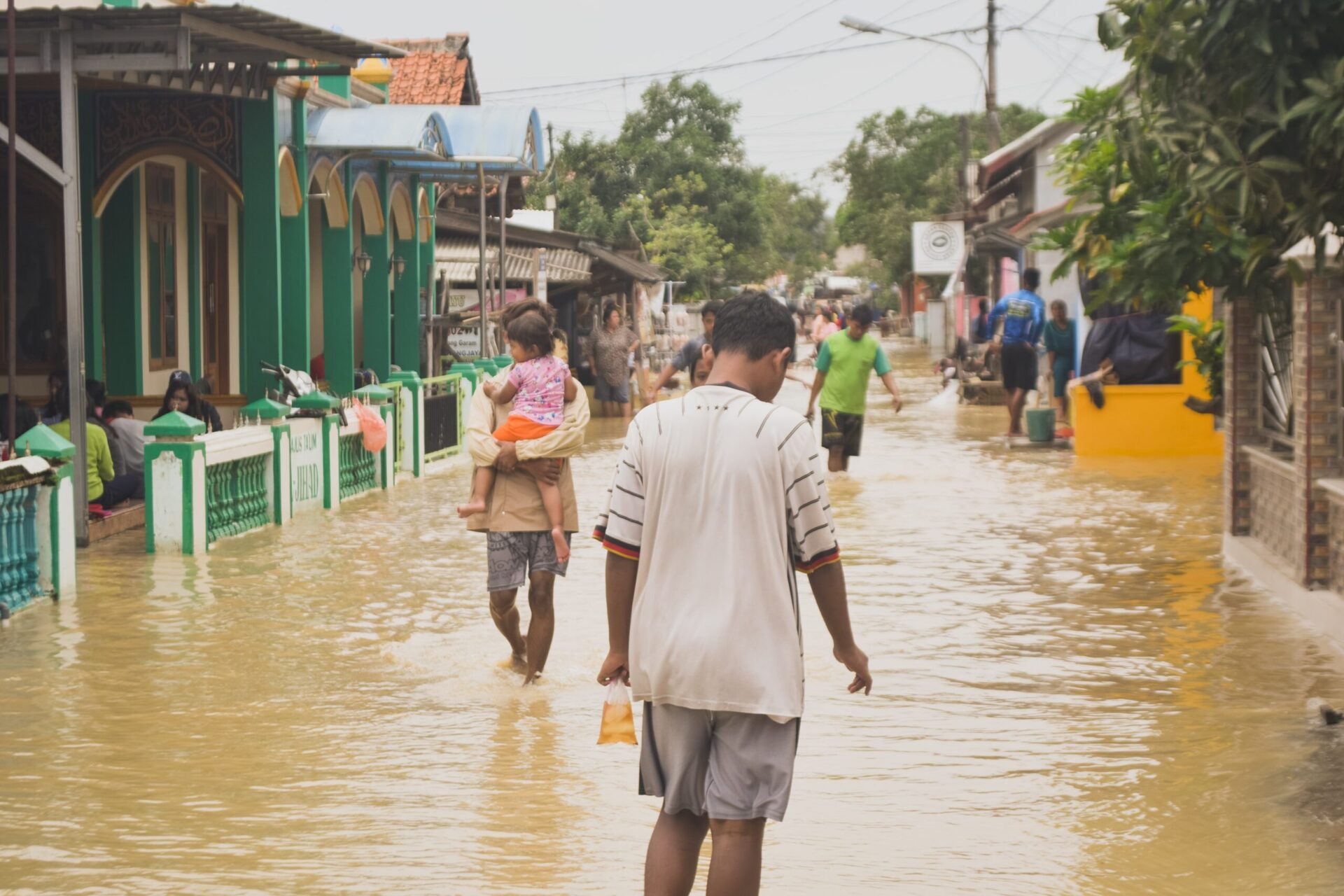 people walk through a flooded street
