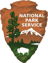 an arrowhead with a tree, a bison, and a mountain within it with the words national park service