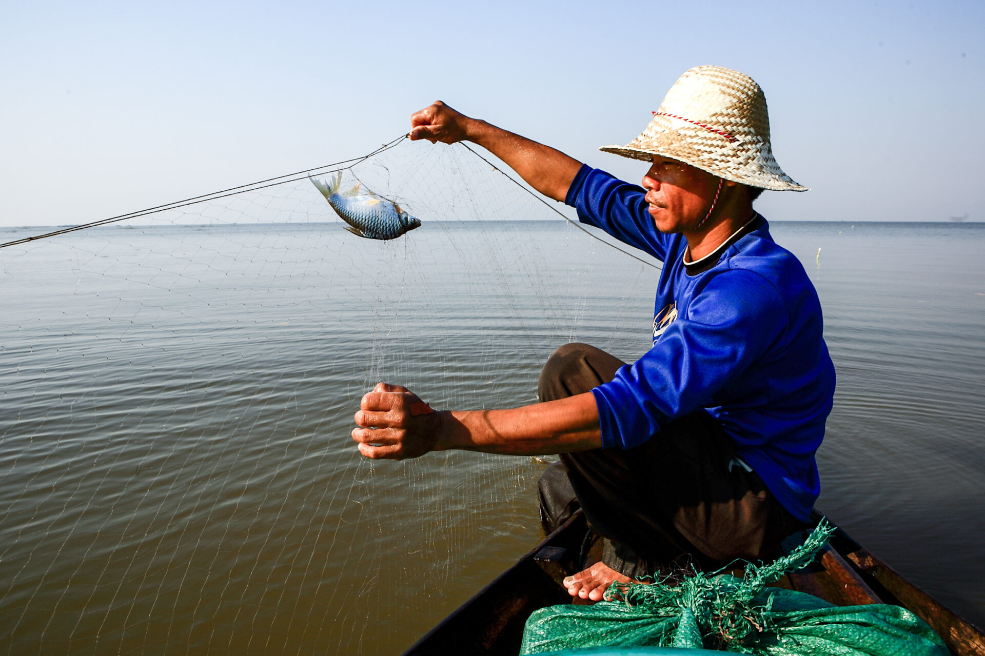A fisherman in the Mekong delta catches a fish.