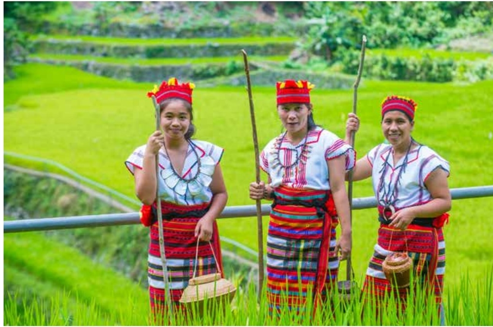 Three women in a field wearing traditional clothing from the Philippines
