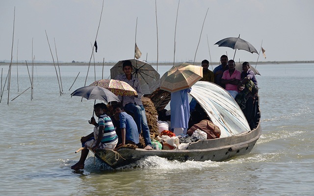 People with umbrellas on a crowded small boat on a river. Picture to illustrate that mental health is important for Trapped Populations.