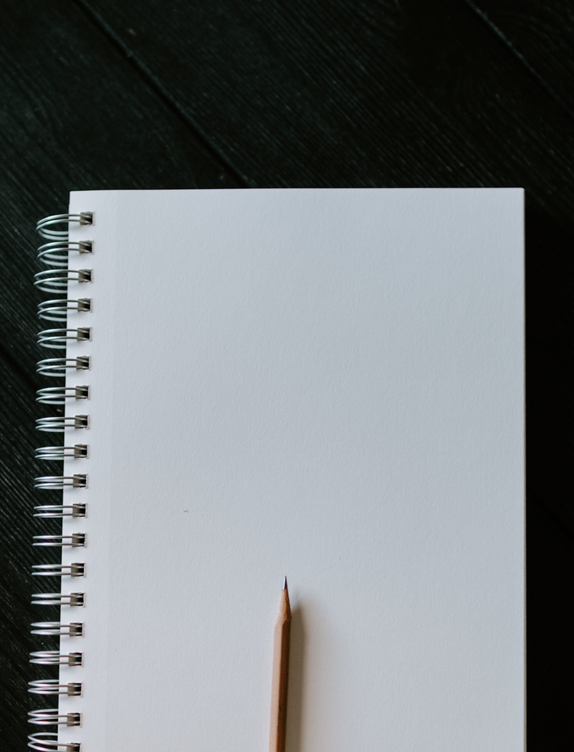 Wooden pencil on blank spiral notebook (Credit: Kelly Sikkema, Unsplash)